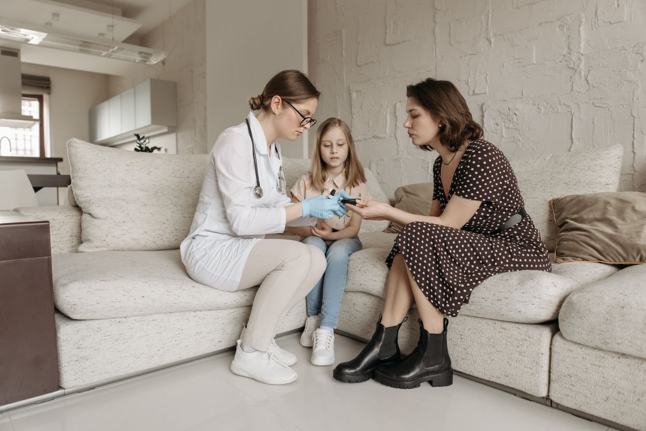 Home A medical professional examines a childs hand while the mother watches closely.