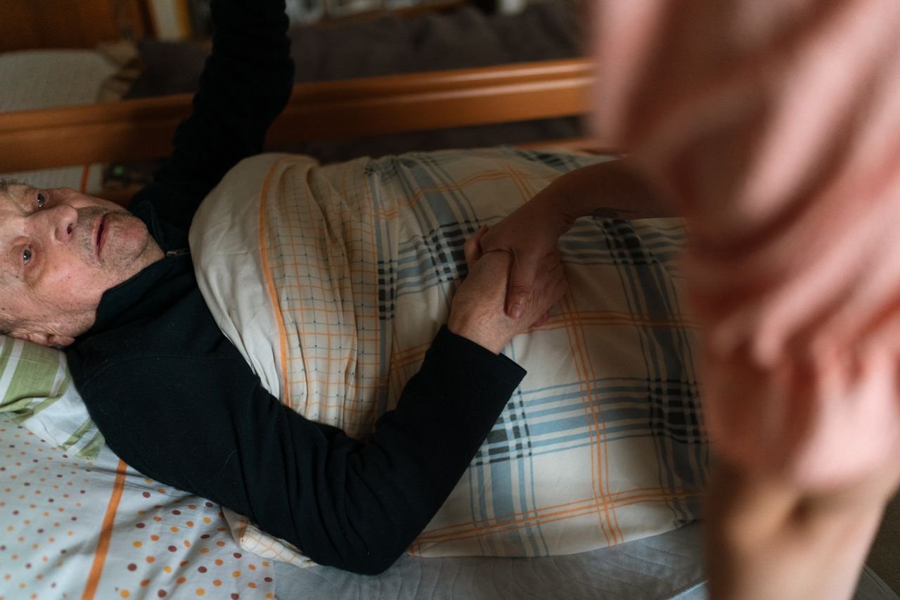 Home A caregiver holding hands with a senior adult, providing support and reassurance at home.
