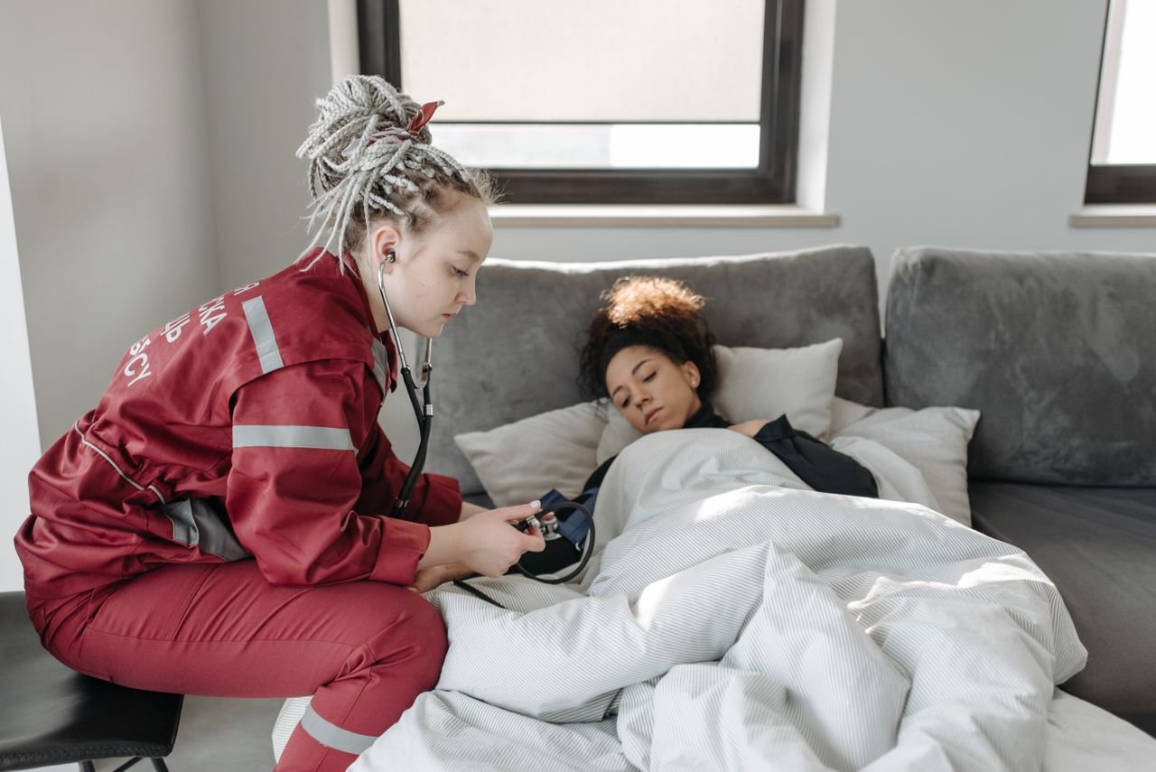 A paramedic checks on a woman in bed, providing home healthcare and support.